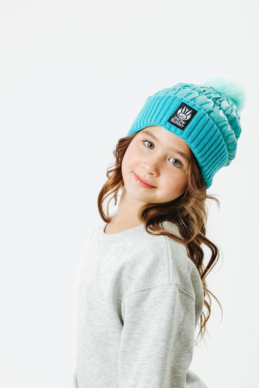 Young girl wearing a blue beanie with a logo on a white background
