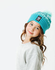 Young girl wearing a blue beanie with a logo on a white background
