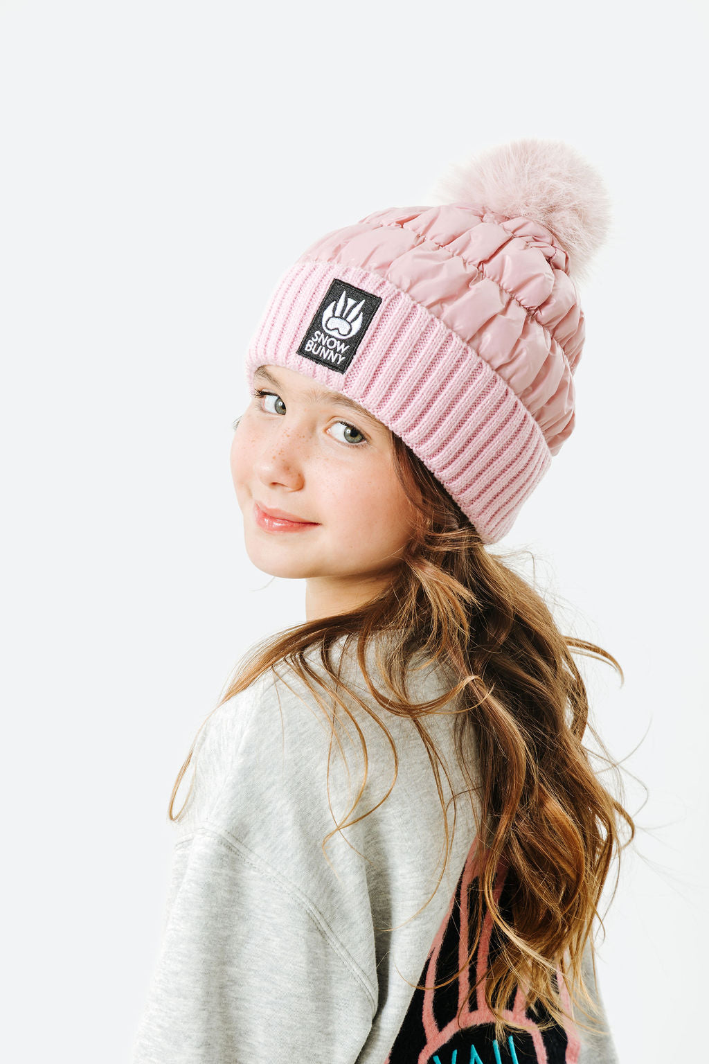 Child wearing a pink knit beanie with a brand logo on a white background