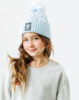 Person wearing a light blue beanie with a logo on a white background