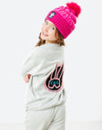 Child wearing a pink beanie and gray sweatshirt with a logo on a white background