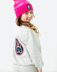 Child wearing a pink beanie and gray sweatshirt with a logo on a white background