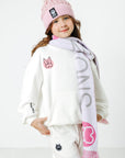 Child wearing a pink beanie and scarf with visible branding on a white background