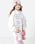 Child wearing a pink beanie and scarf with visible branding on a white background