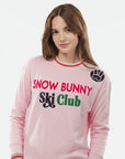 Person wearing a pink 'Snow Bunny Ski Club' outfit on a white background